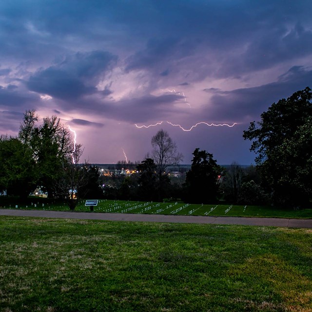 A lighting strike lights up the sky over the cemetery