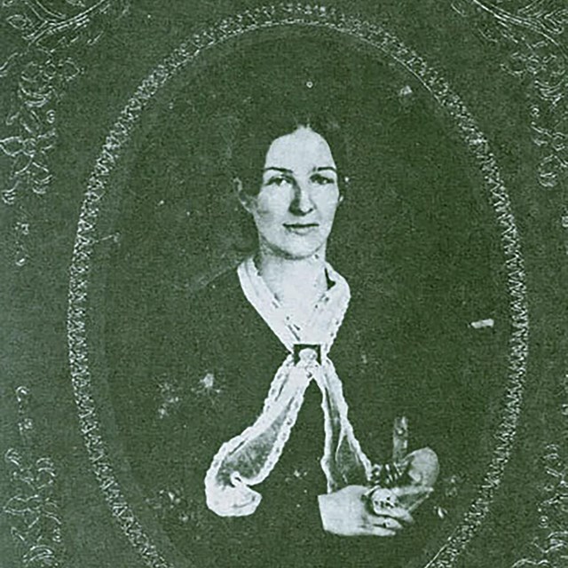 A black and white image of a middle aged woman in a dress 