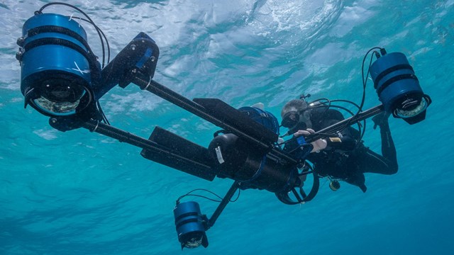 Scuba diver holding a large underwater camera