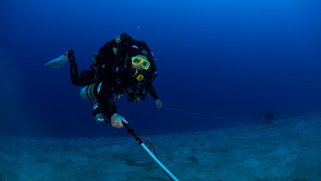 Scuba diver using a metal detector underwater