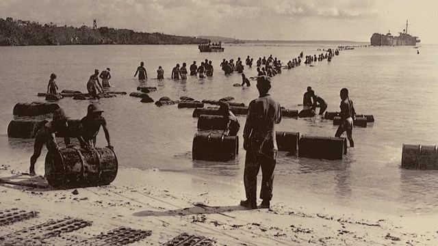 Group of soldiers oversee the unloading of supplies on a beach