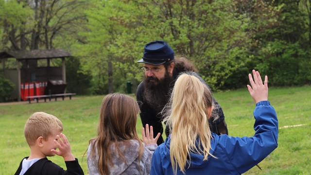 A man dressed in union uniform speaks to a line of children