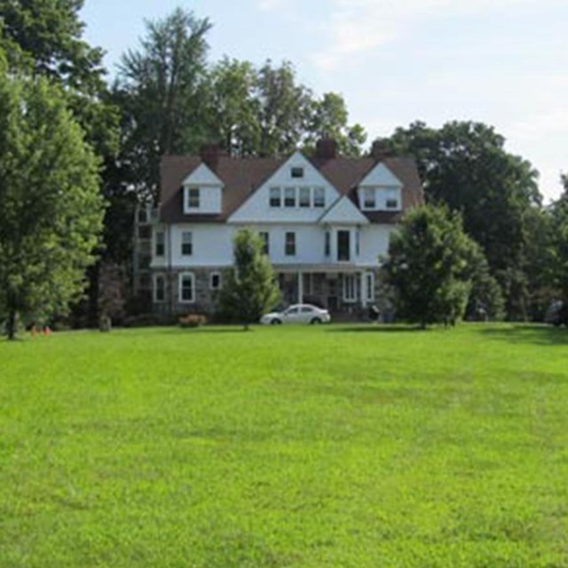 photo of the exterior of a house surrounded by lawn and trees