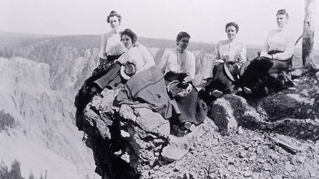Historic photograph of employees sitting on the rim of a canyon