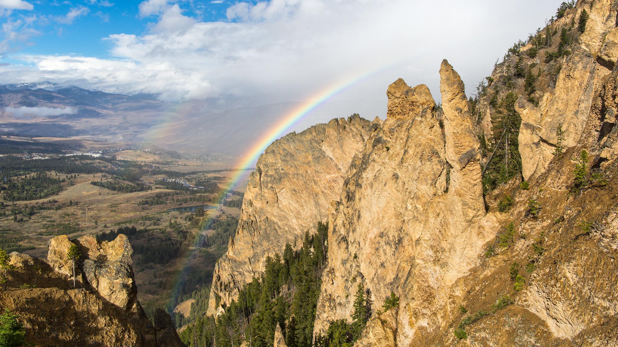 A rainbow frames rocky cliffs.