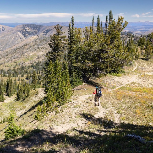 Hiker on a ridge with mountains in the distance