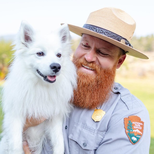 Ranger holding a white dog