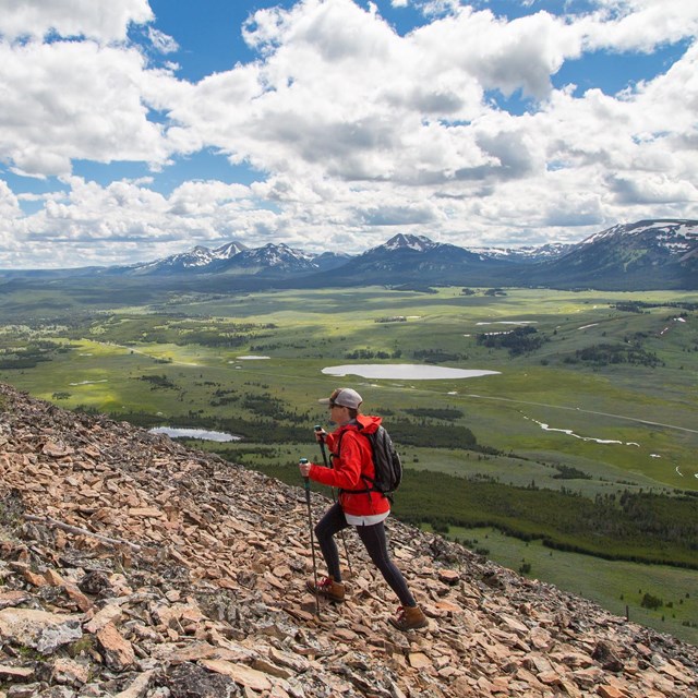 A person hikes up a trail with mountain views.