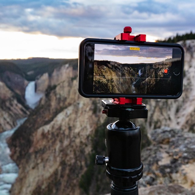 Photo of a camera taking video of a canyon at sunset.
