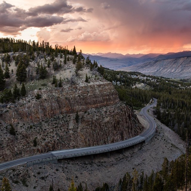 a winding paved road through a canyon at sunset