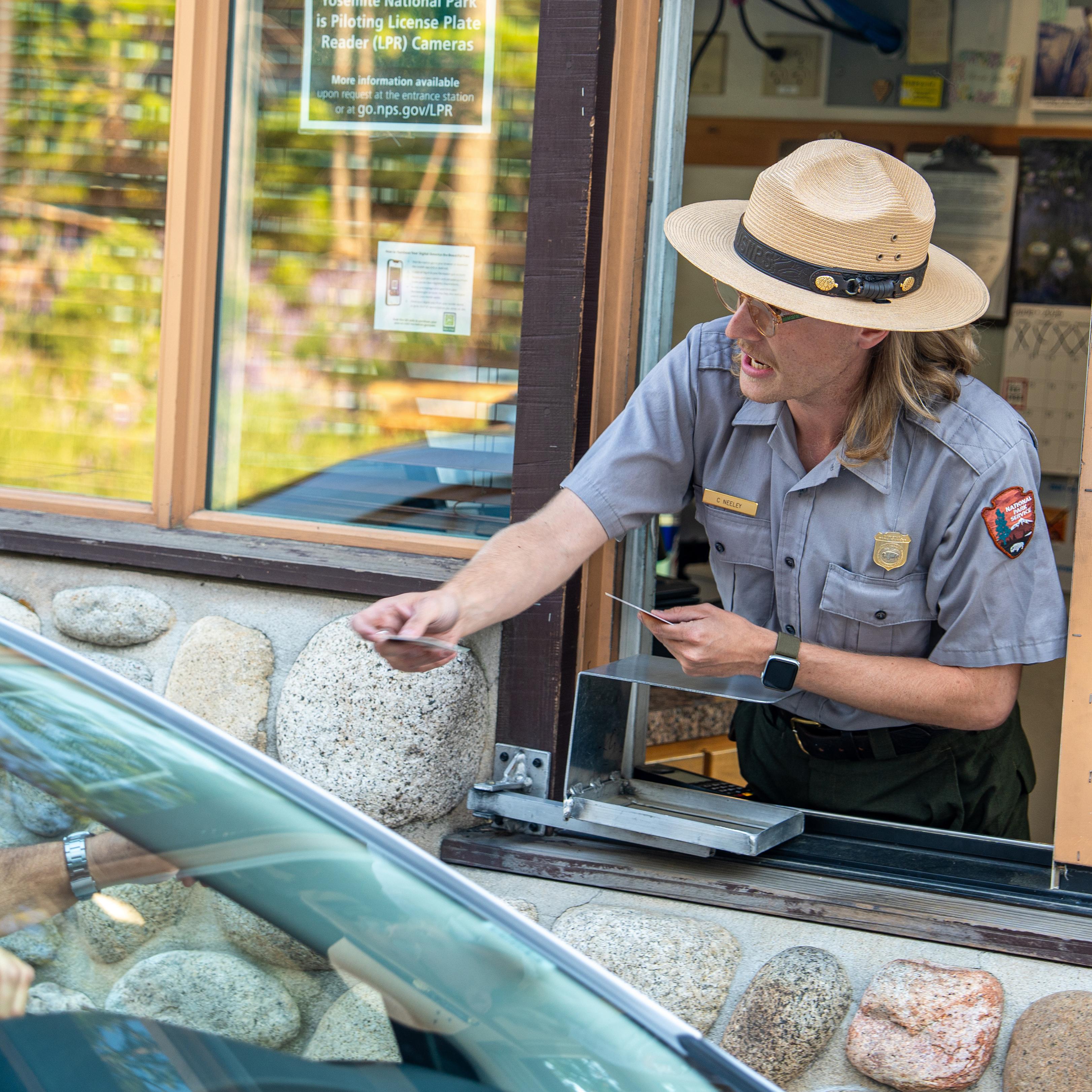 Park Ranger interacting with a visitor in a car at the entrance station