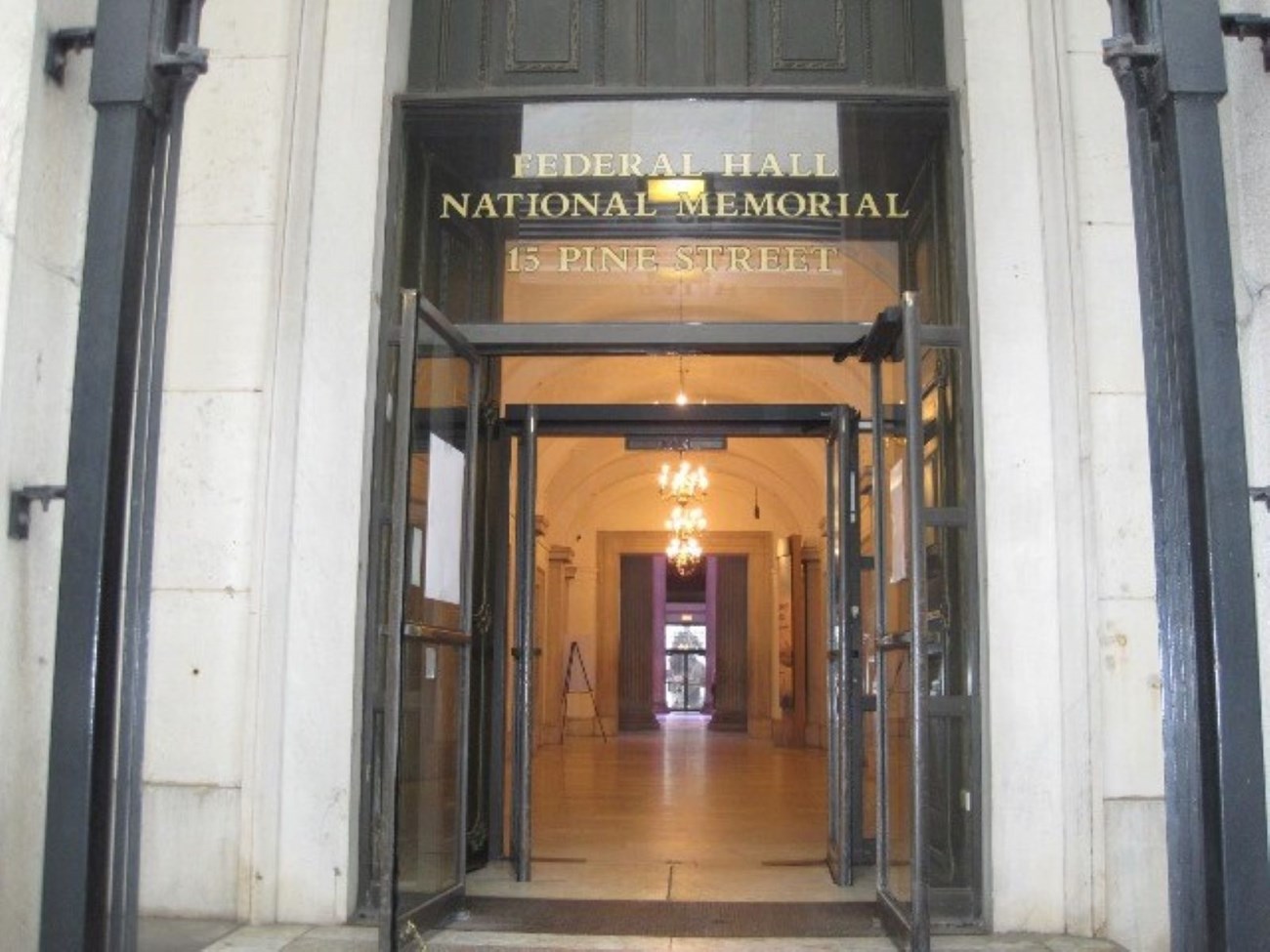 A glass doorway stands open to a lobby lit by incandescent light.