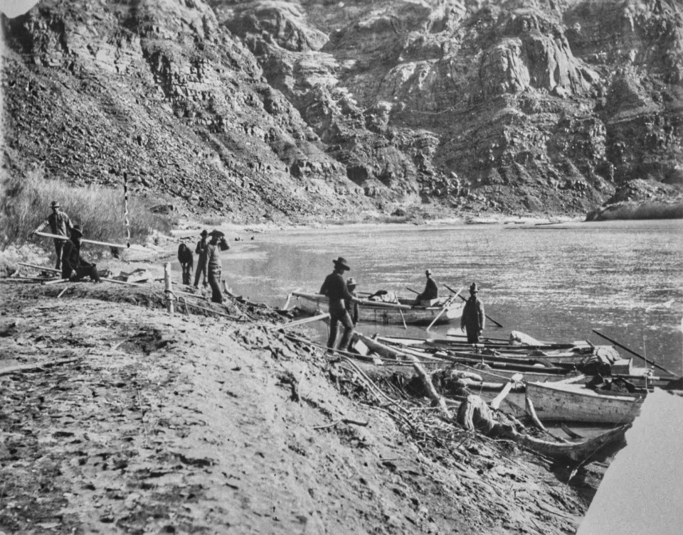 Men and boats on river with cliffs