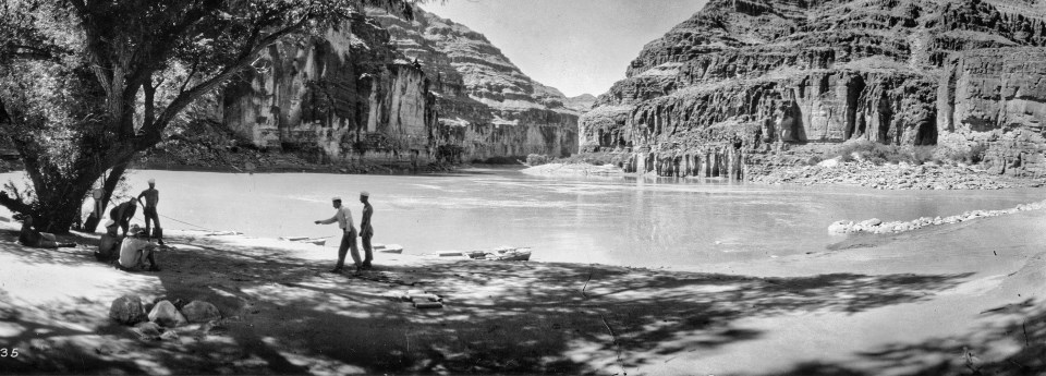 Men playing horseshoes next to river, cliffs in background