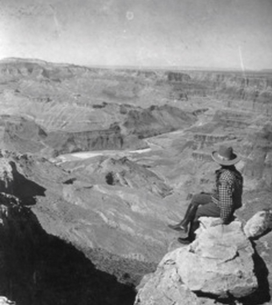 Man sitting on rock looking at river canyon