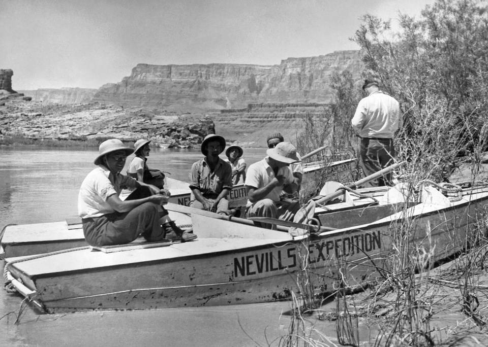 Men and women in a boat on a river with cliffs in the background
