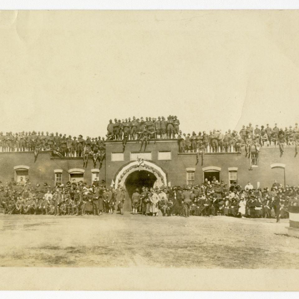 Presumably during a celebration of sorts, soldiers surround and sit/stand on top of the Sallyport, Fort McHenry’s entrance and exit onto the parade ground where the flag mast stands.