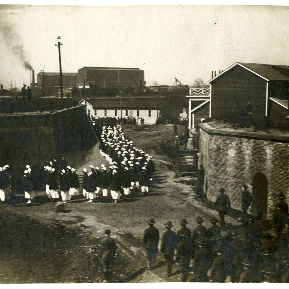 A procession of nurses march in to the SallyPort of Fort McHenry, as rows of soldiers wait and watch for their turn to proceed in.