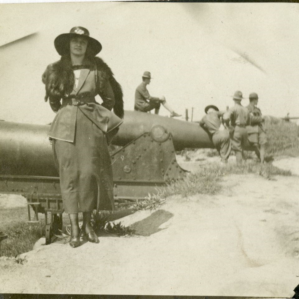 A woman who reclines on a Rodman Canon, while soldiers behind her horse around with a different canon.