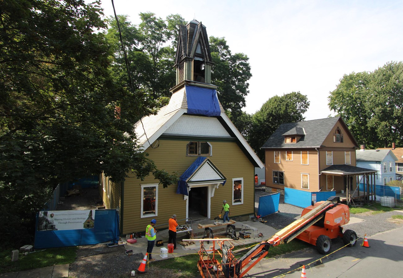 An image of the exterior of a church under construction, with equipment and workers standing outside.