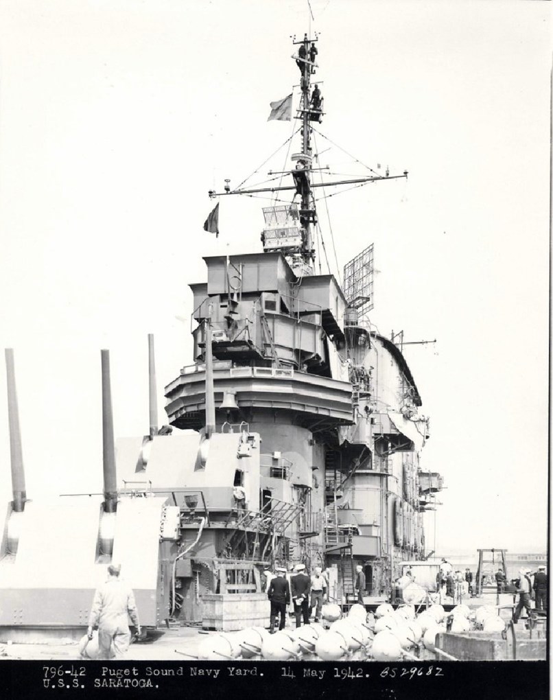 The top of an iron ship with guns mounted on the deck and command tower.