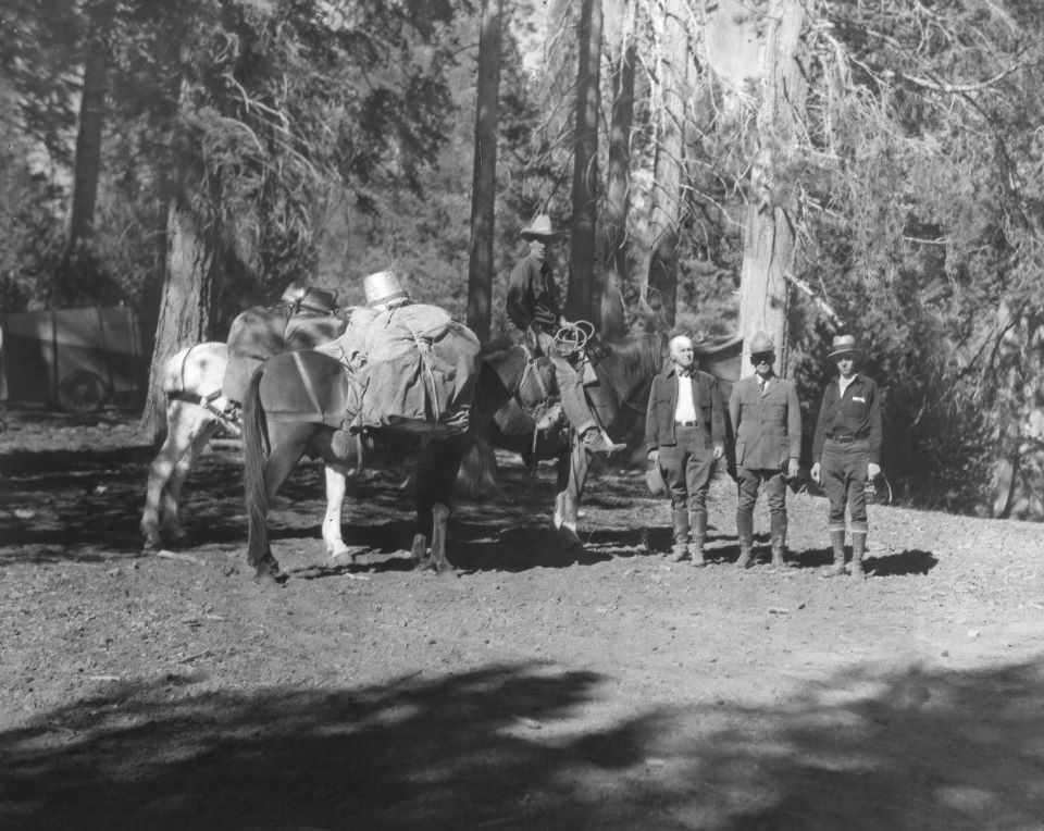Black and white photo of park rangers with horses.