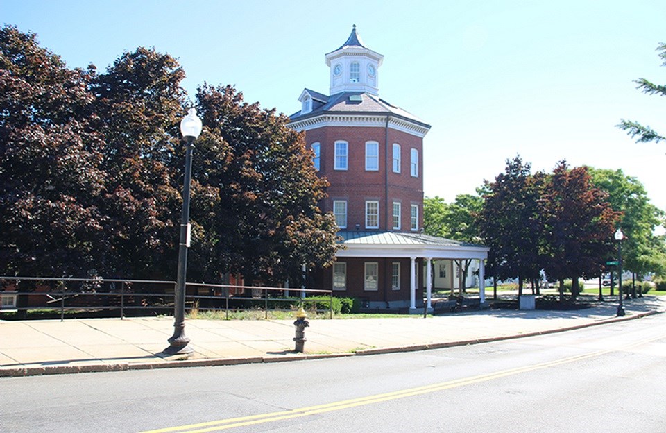 The Muster House, an octagonal building with a cupola surrounded by a street with mid-century cars.