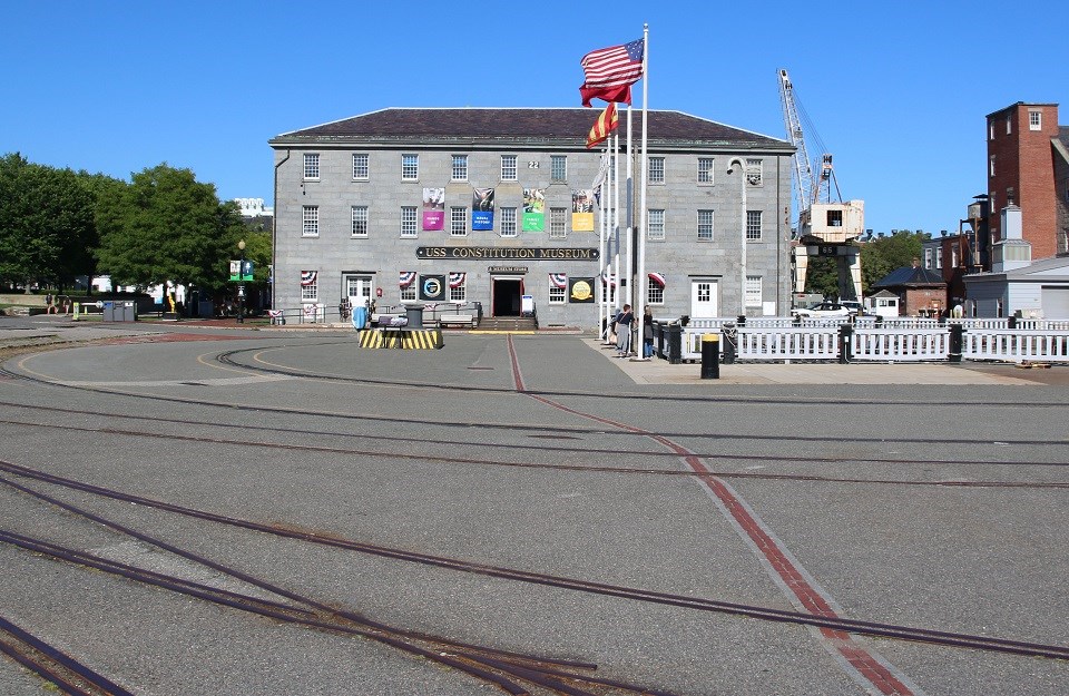 USS Constitution Museum building in the distance with mid-century cars in front of it.