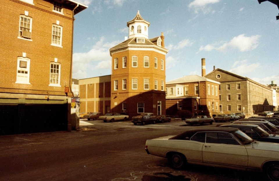 The Muster House, an octagonal building with a cupola surrounded by a street with mid-century cars.