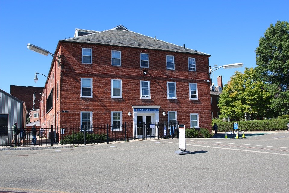 black and white photo of a brick building with a flagpole and two vintage cars