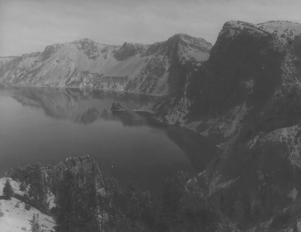 Black and white photo of a lake surrounded by steep-sided cliffs.