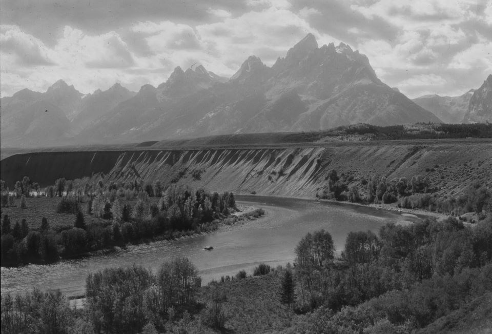 Black and white photo looking across a winding river to a mountain range.