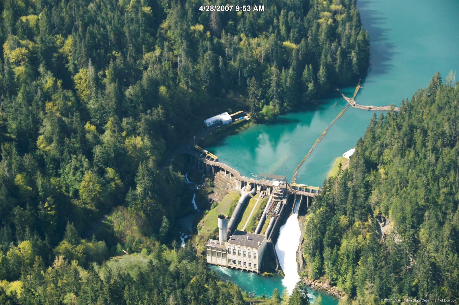 Aerial view of dam structure in river valley surrounded by trees