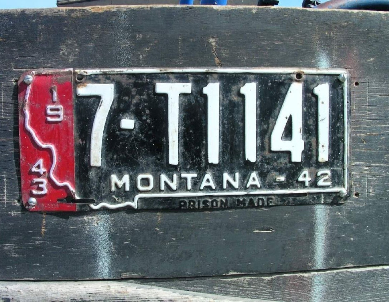 A green license plate with numbers and Montana 1944 over a black license plate with the shape of Montana and labeled Montana-42