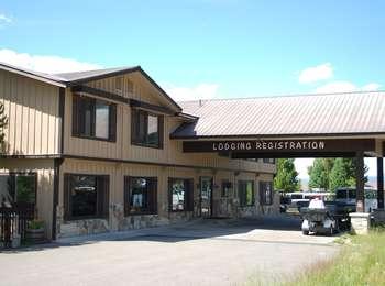 Lodging registration building for Signal Mountain Lodge. Tan two-story building with dark brown trim. Sign over parking structure reads 