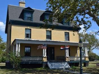 The front porch of this officerâ€™s house, now a museum, flies the stars and stripes on a bright summer day. 