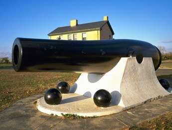 The painted black barrel of this 20-inch Rodman gun, now retired for over a century, sits on a white concrete mount.