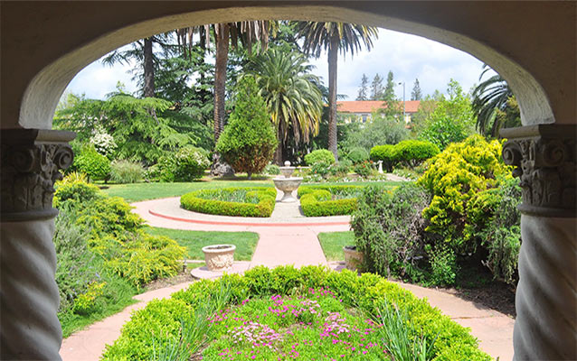 View looking through a portal with brick paths and fountain surrounded formal landscaping