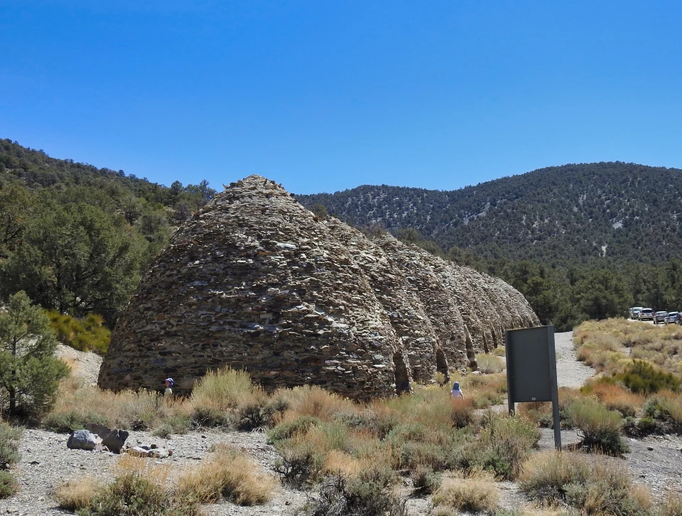 Black & White photo of Conical shaped brick ovens with hills behind
