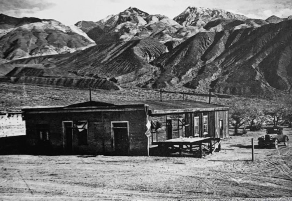 Old building and car with desert mountains in background