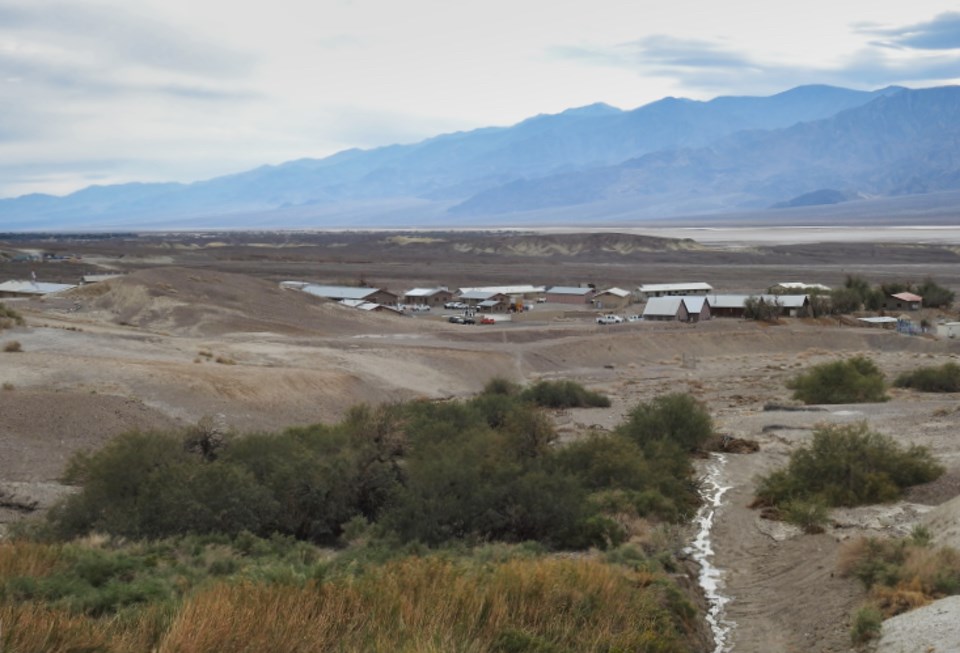 Buildings visible across desert wash with mountains in background.