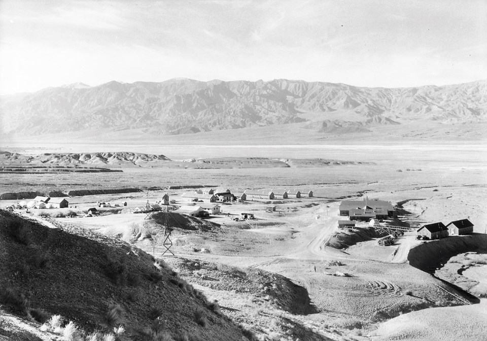 Buildings visible across desert wash with mountains in background.