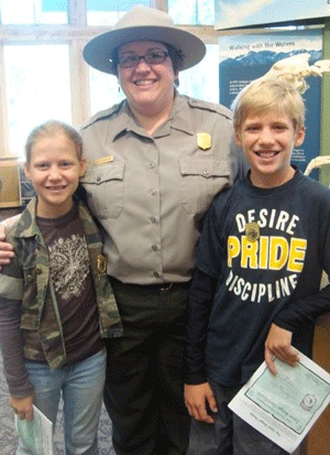 A ranger stands with two junior rangers