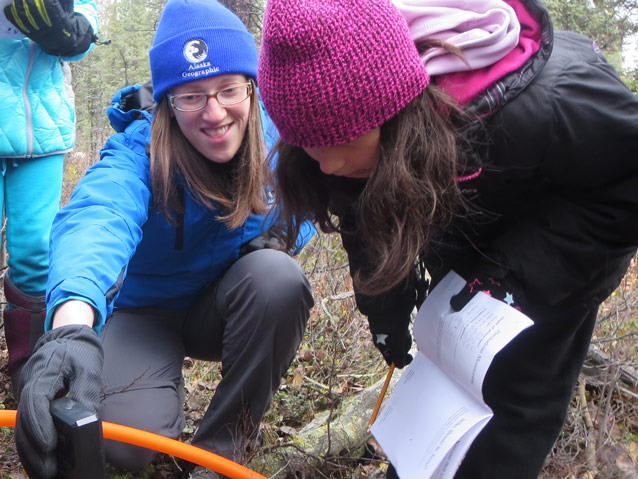 a student leans over to read a digital thermometer held by an instructor