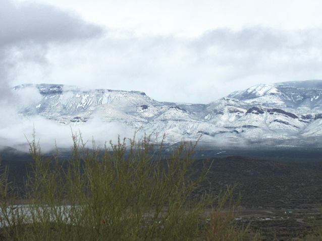 Snow blanketing highlands, viewed from an area free of snow.