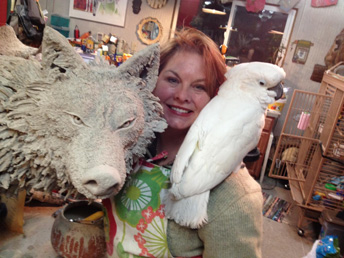 Woman in artist studio with bird and wolf sculpture