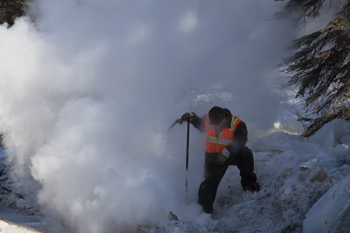 a road worker stands in a cloud of steam