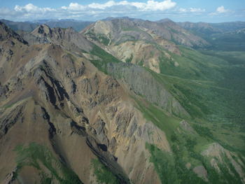 rocky mountains erupt out of green hillsides