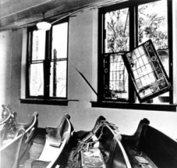 B&W photo of blown on windows and haphazard church pews