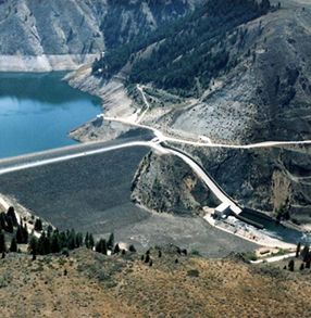 Photo of Anderson Ranch Dam from a far distance surrounded by blue water and tall mountains 